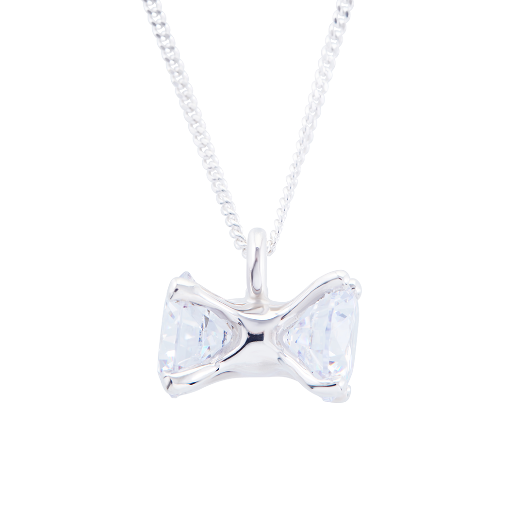 Silver bow-shaped pendant with clear gemstones on a white background