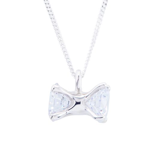 Silver bow-shaped pendant with clear gemstones on a white background
